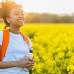 Outdoor Portrait Of Beautiful Happy Laughing Mixed Race African American Girl Teenager Female Young Woman With Drinking Water Bottle In A Field Of Yel